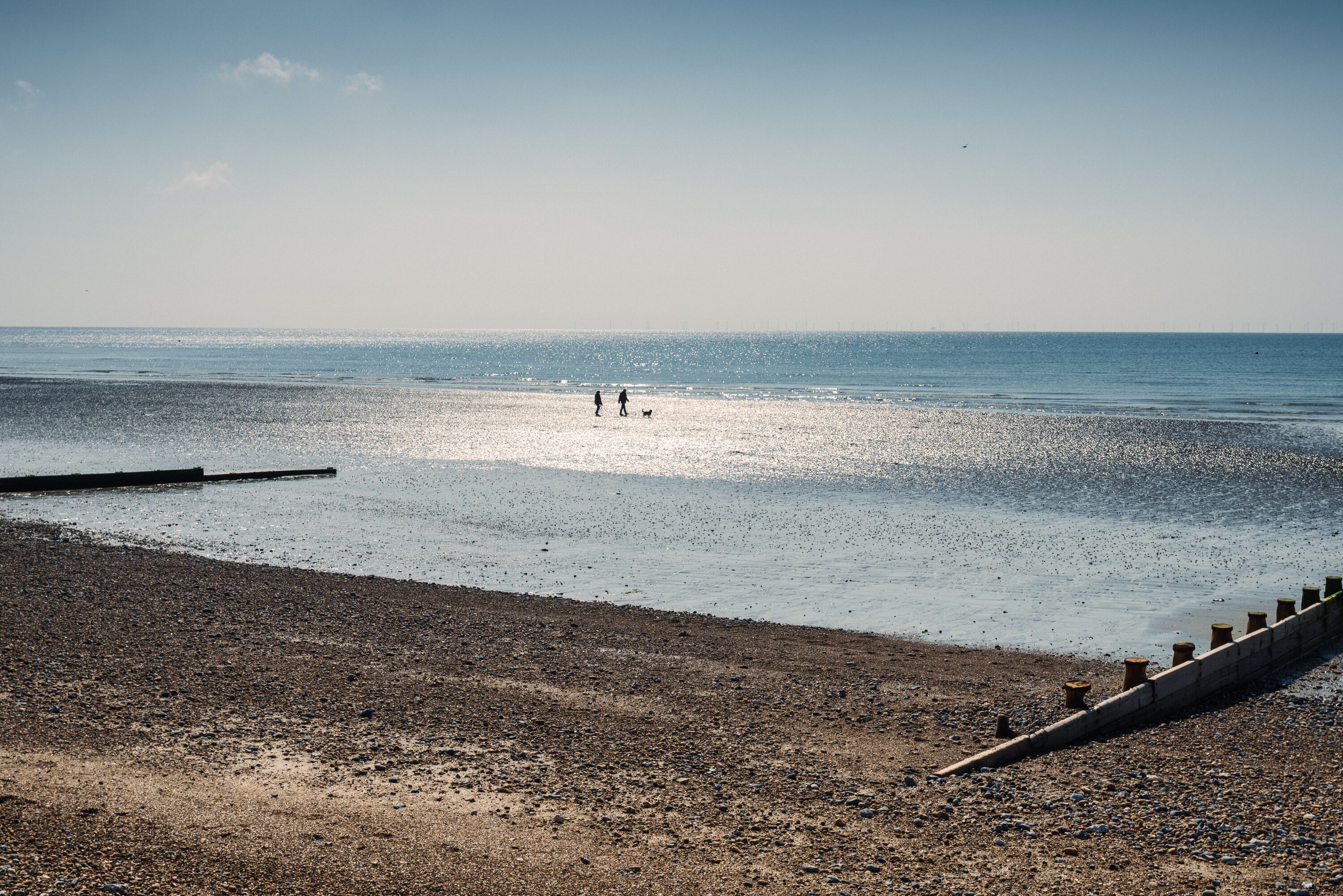 A beach with a rocky shoreline and a concrete barrier.