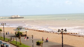 A beach with a promenade, a pier in the background, and a gazebo. - The Burlington Hotel (Worthing)