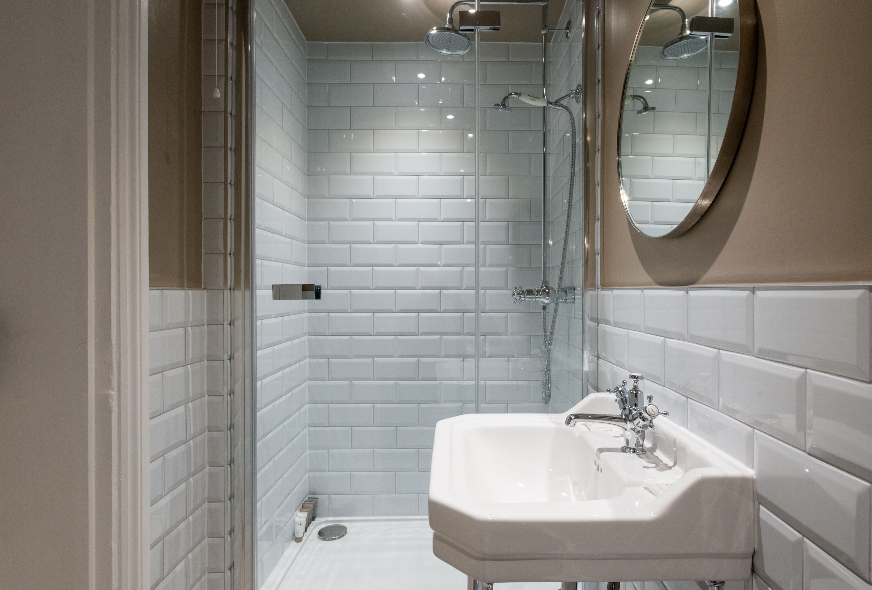 A modern bathroom with white subway tiles, a white sink, and a shower area.