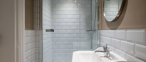 A modern bathroom with white subway tiles, a white sink, and a shower area.