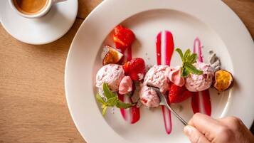 Un plato de postre con helado, fresas y una ramita de menta.