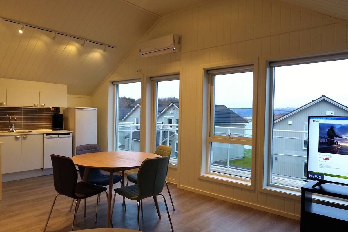 A modern kitchen with white cabinets, a built-in oven, and a large window overlooking a residential area.