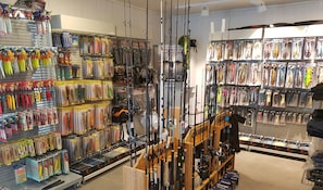 A store with fishing rods and lures on shelves and racks.