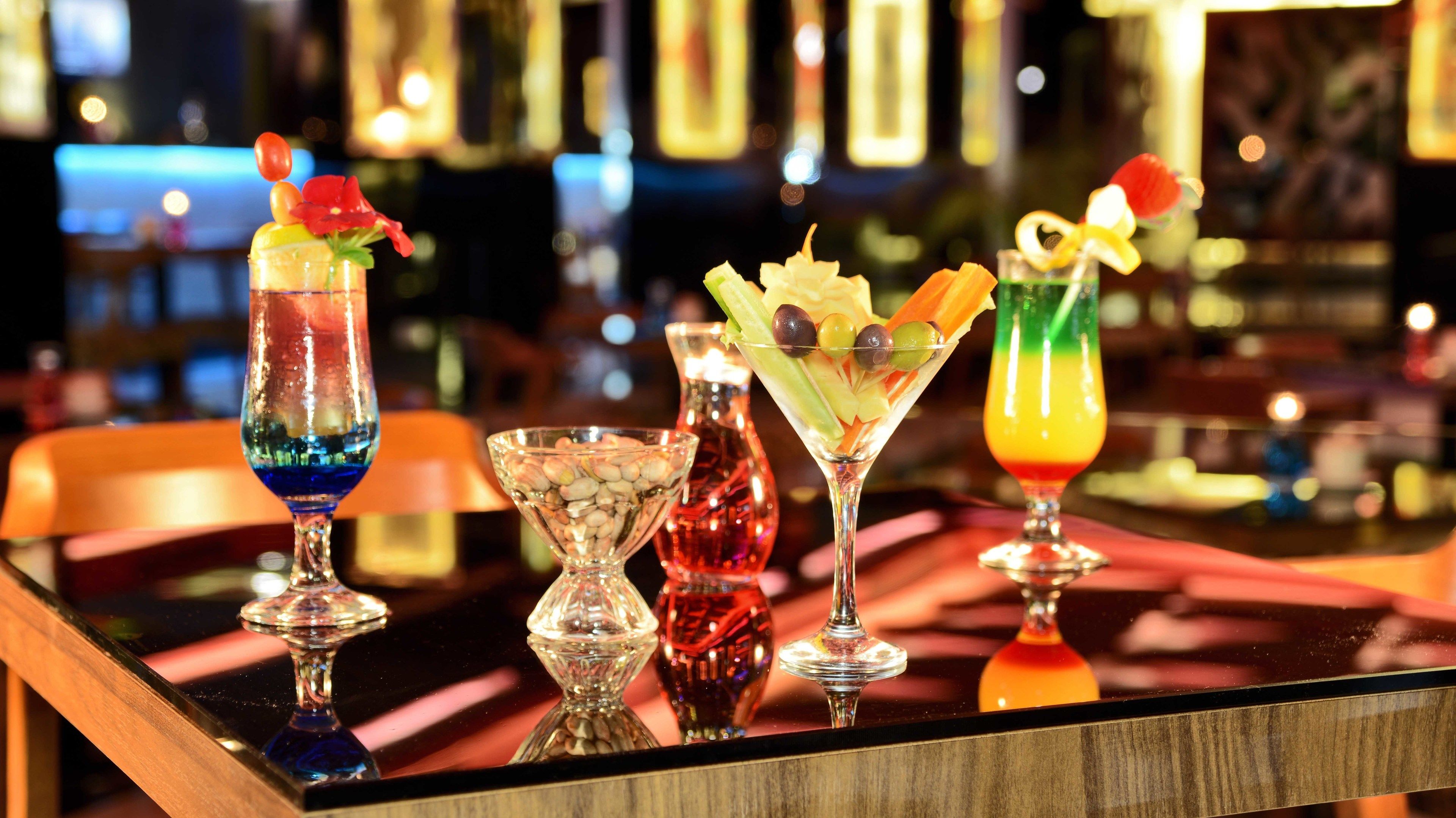 A bar with four cocktails and a decorative vase.