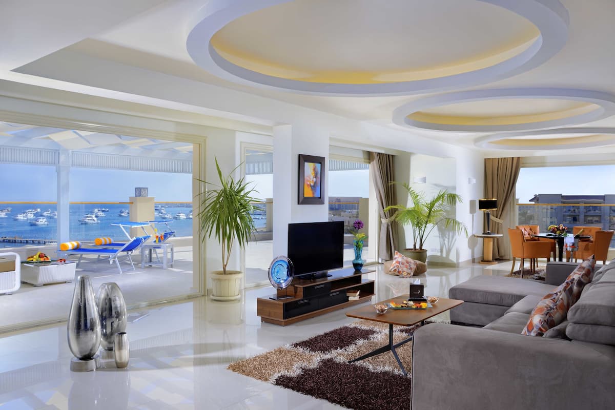 Een moderne woonkamer met een grote televisie, comfortabele zitplaatsen en uitzicht op zee.