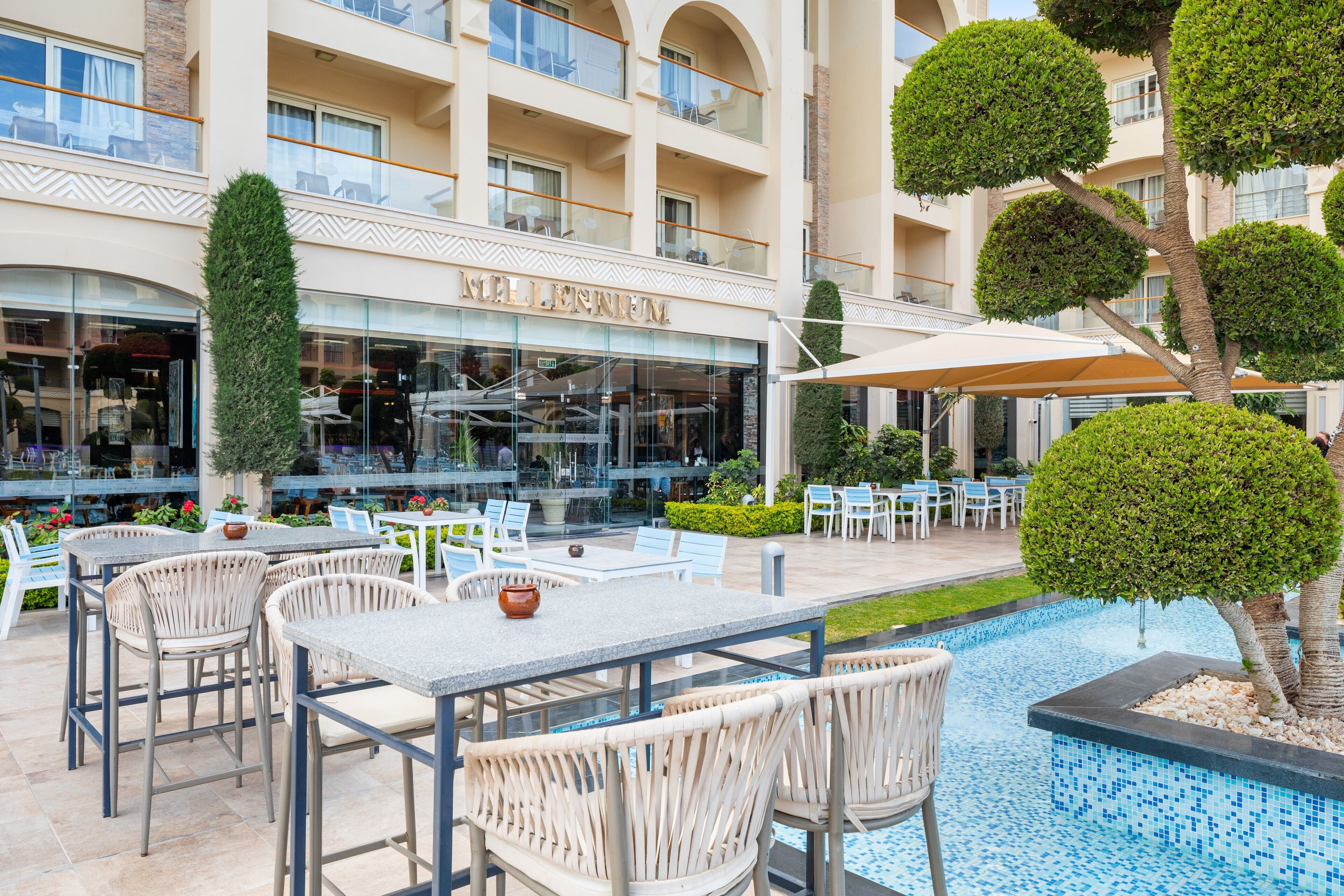 A hotel with a pool area, outdoor seating, and a building facade with balconies.