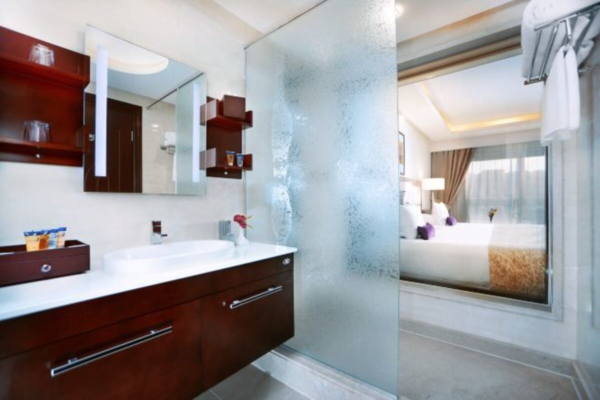 Une salle de bain moderne avec un grand miroir, un lavabo blanc et une cabine de douche en verre.