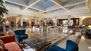 Eine geräumige Lobby mit hoher Decke, großen Fenstern und einer zentral platzierten Dekorationsskulptur.