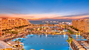 Ein Resort mit einem großen Schwimmbad, mehreren Hotelgebäuden und Booten im Hintergrund.