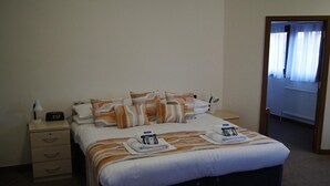 A hotel room with a bed, bedside tables, and a nightstand. - Robinson College - Cambridge University - Campus Accommodation (Cambridge)