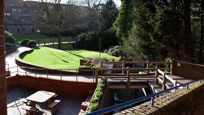 A courtyard with a wooden deck, picnic table, and a view of a building in the background. - Robinson College - Cambridge University - Campus Accommodation (Cambridge)