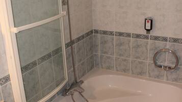 Un baño con ducha de vidrio, bañera y perchero para toallas.