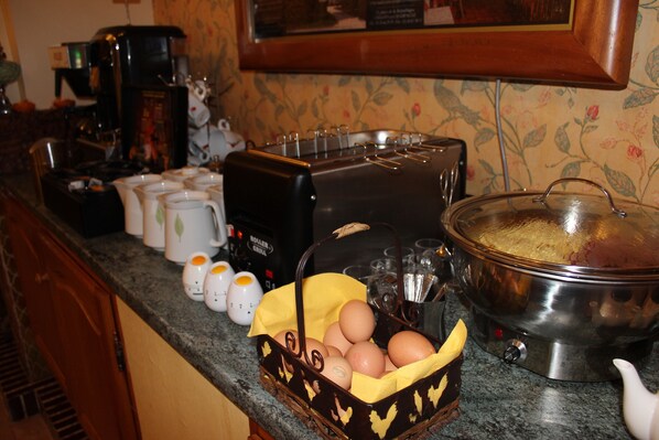 A kitchen counter with a coffee maker, toaster, and a pot. There are eggs in a basket and salt and pepper shakers.