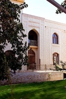 A building with a symmetrical facade, featuring arched windows and doors, and a balcony with ornate railings.