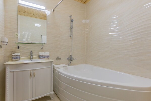 A bathroom with a bathtub, a sink with a mirror, and a shower. - L'Argamak Hotel (Samarkand)