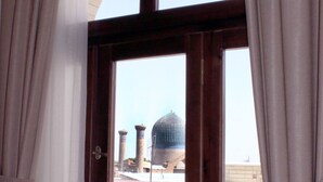 Una ventana con cortinas, vista de un edificio con una cúpula y una pared de ladrillo.