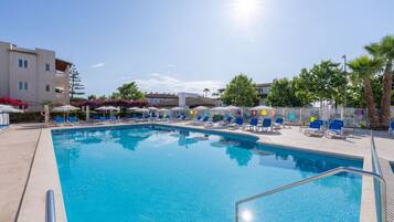 Una piscina al aire libre, sombrillas, tumbonas