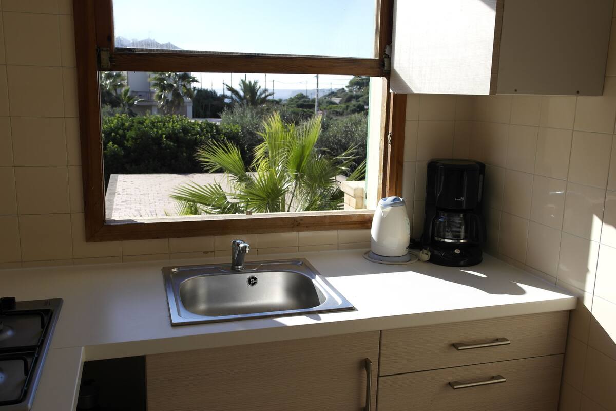 A kitchen with a window, sink, and coffee maker.