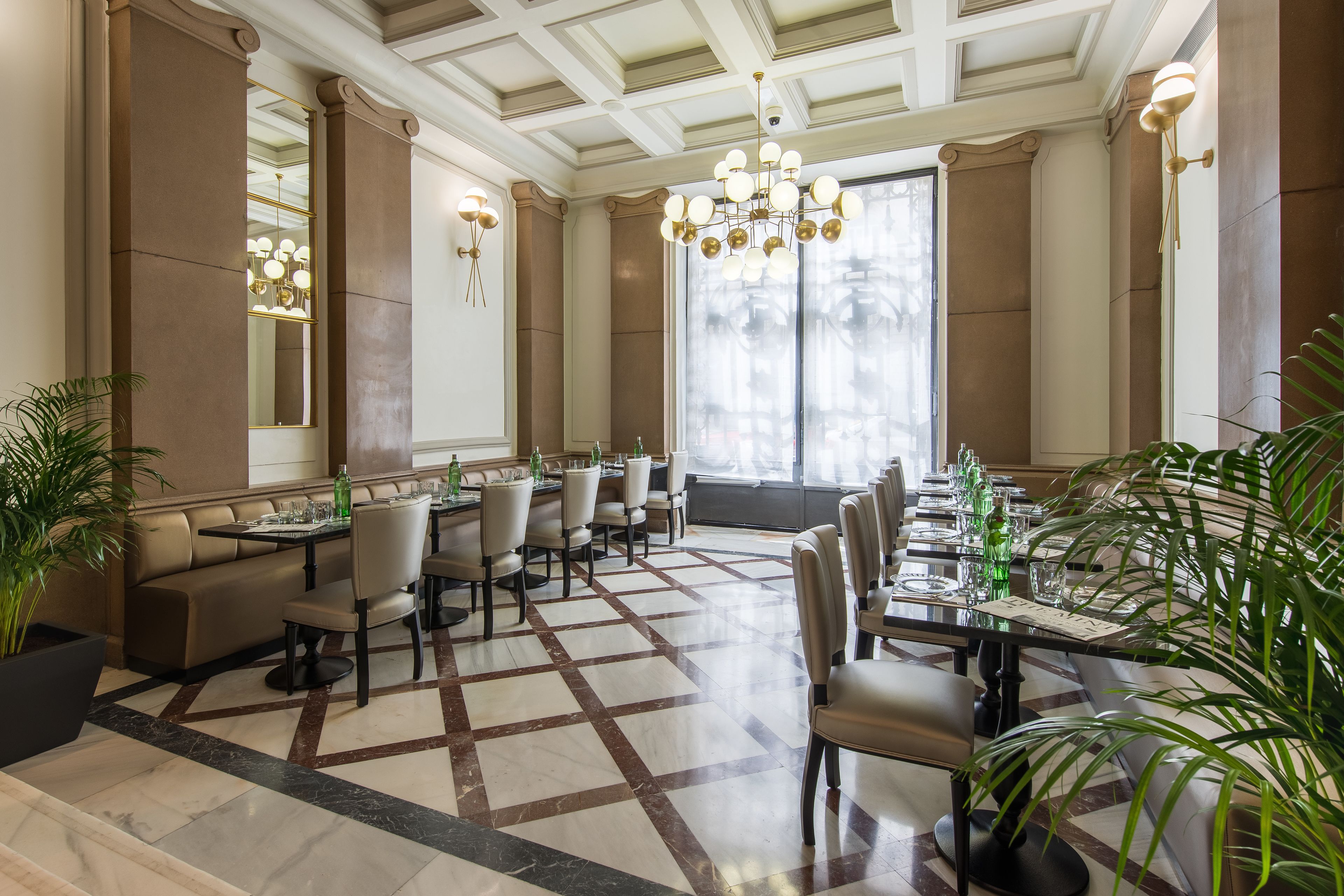 A spacious dining area with high ceilings, large windows, and elegant chandeliers.
