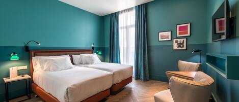 Une chambre d’hôtel avec deux lits, un bureau, une chaise et un téléviseur.