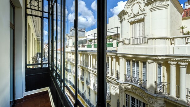 A view from a balcony with a glass railing overlooking a historic building with ornate architecture and a clock tower. - Hotel Vincci The Mint (Madrid)
