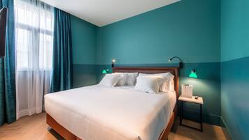 Una cama bien hecha en una habitación con paredes color turquesa, suelo de madera y dos lámparas de noche.