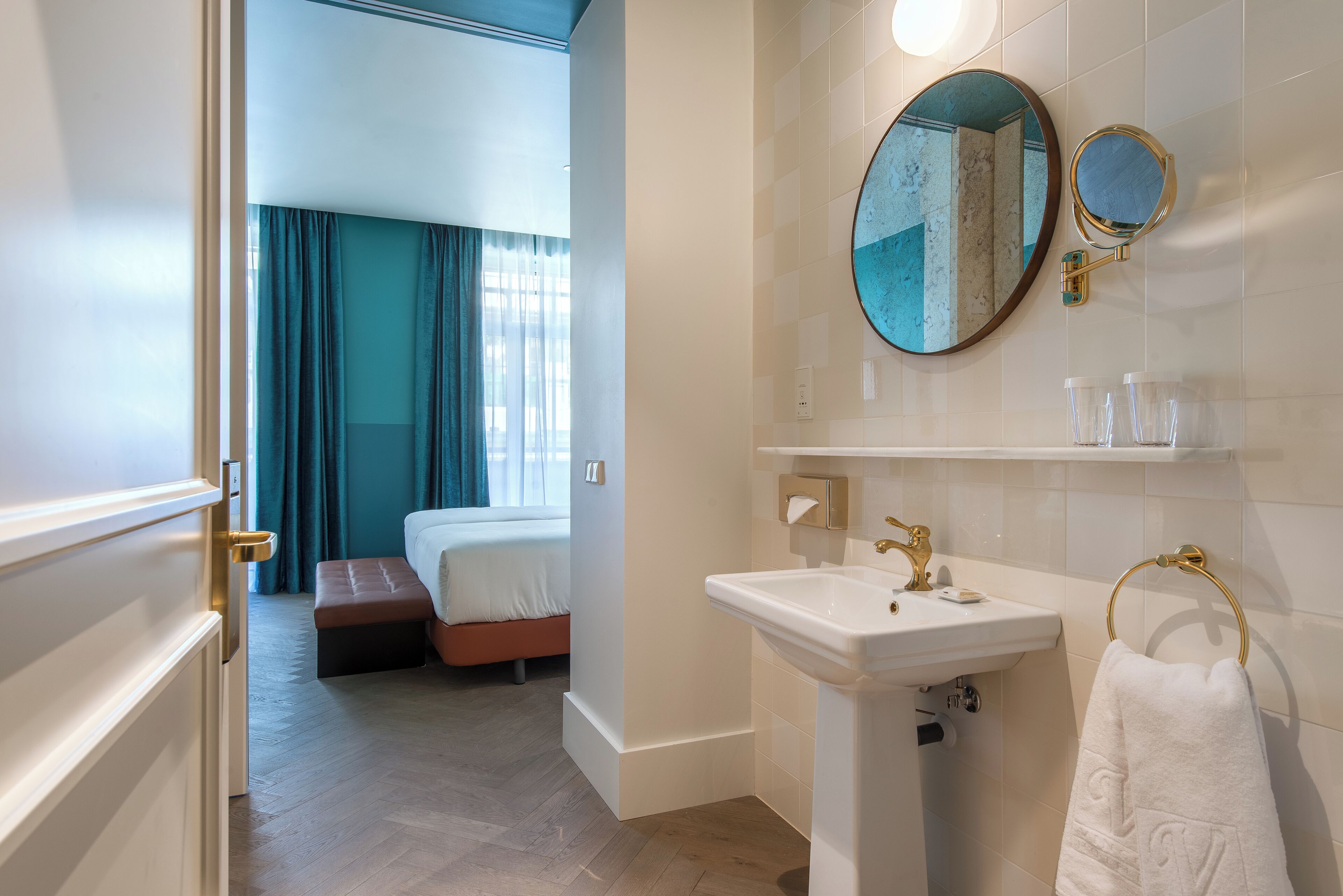 A hotel bathroom with a sink, mirror, and towel rack.