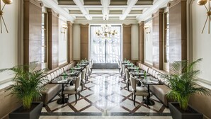 A formal dining room with a long table, multiple chairs, and potted plants. - Hotel Vincci The Mint (Madrid)
