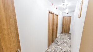 A narrow hallway with patterned flooring, wooden doors, and a ceiling light fixture. - Kaplan Hotel Jerusalem (Jerusalem)