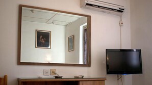 A room with a wooden cabinet, a large mirror, and a flat-screen TV mounted on the wall. - Kaplan Hotel Jerusalem (Jerusalem)