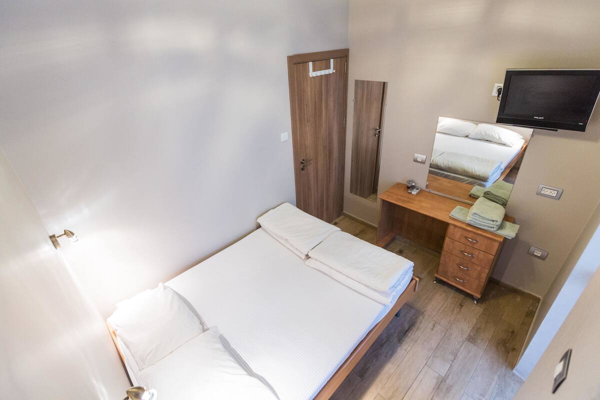 Un dormitorio con una cama, un aparador de madera, un televisor y una puerta.
