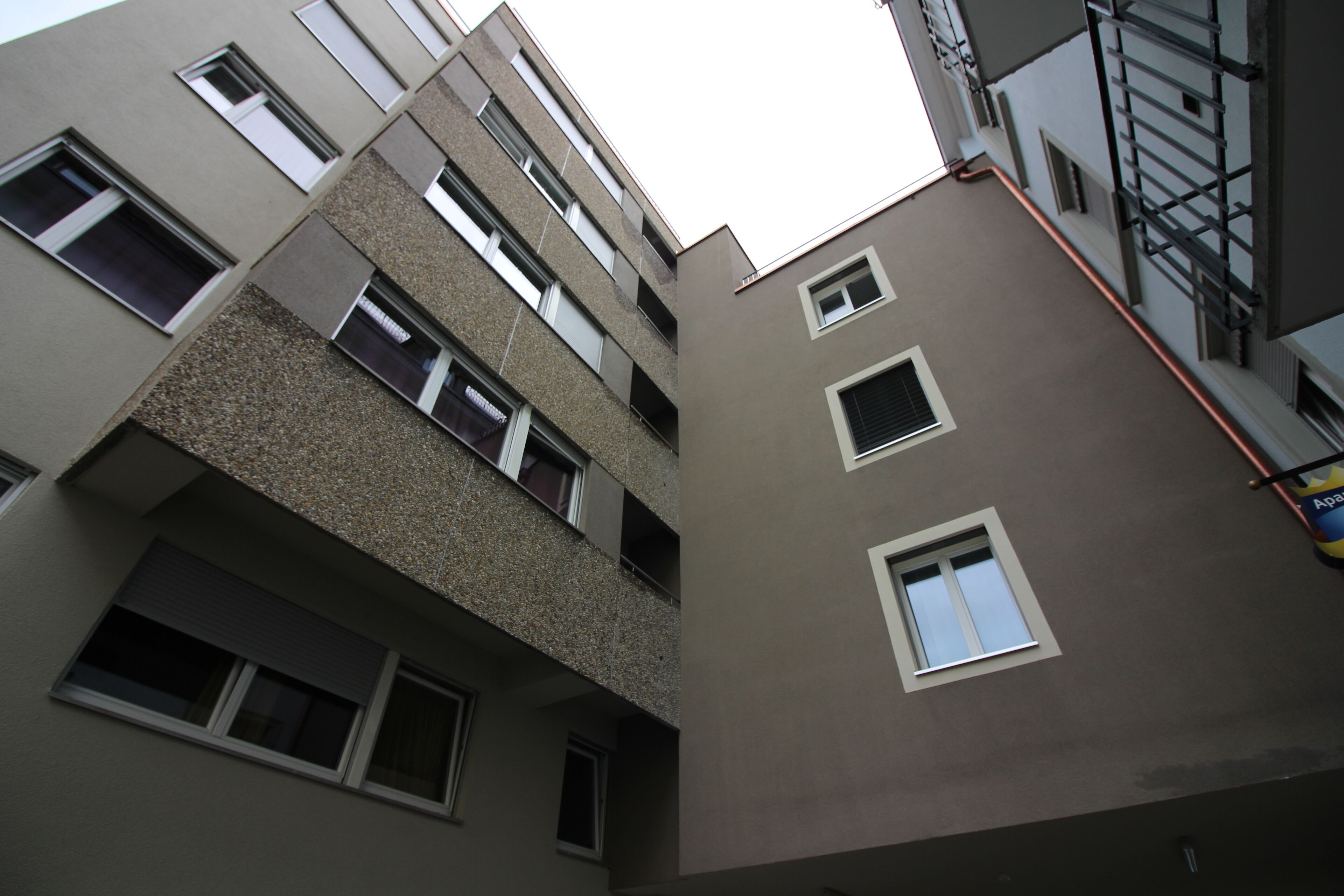 A multi-story building with a modern architectural design, featuring balconies and multiple windows.