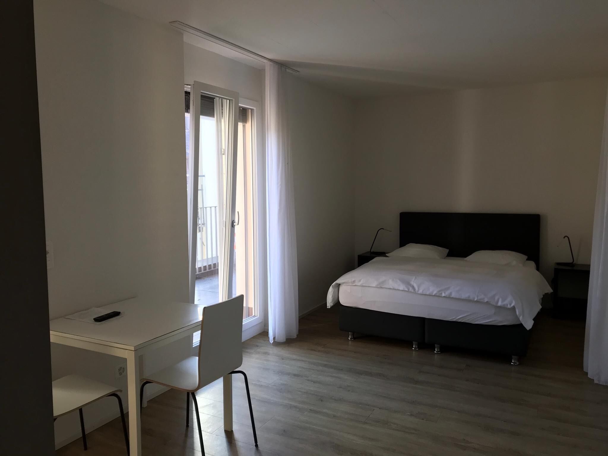 A bedroom with a bed, a desk, and a chair.