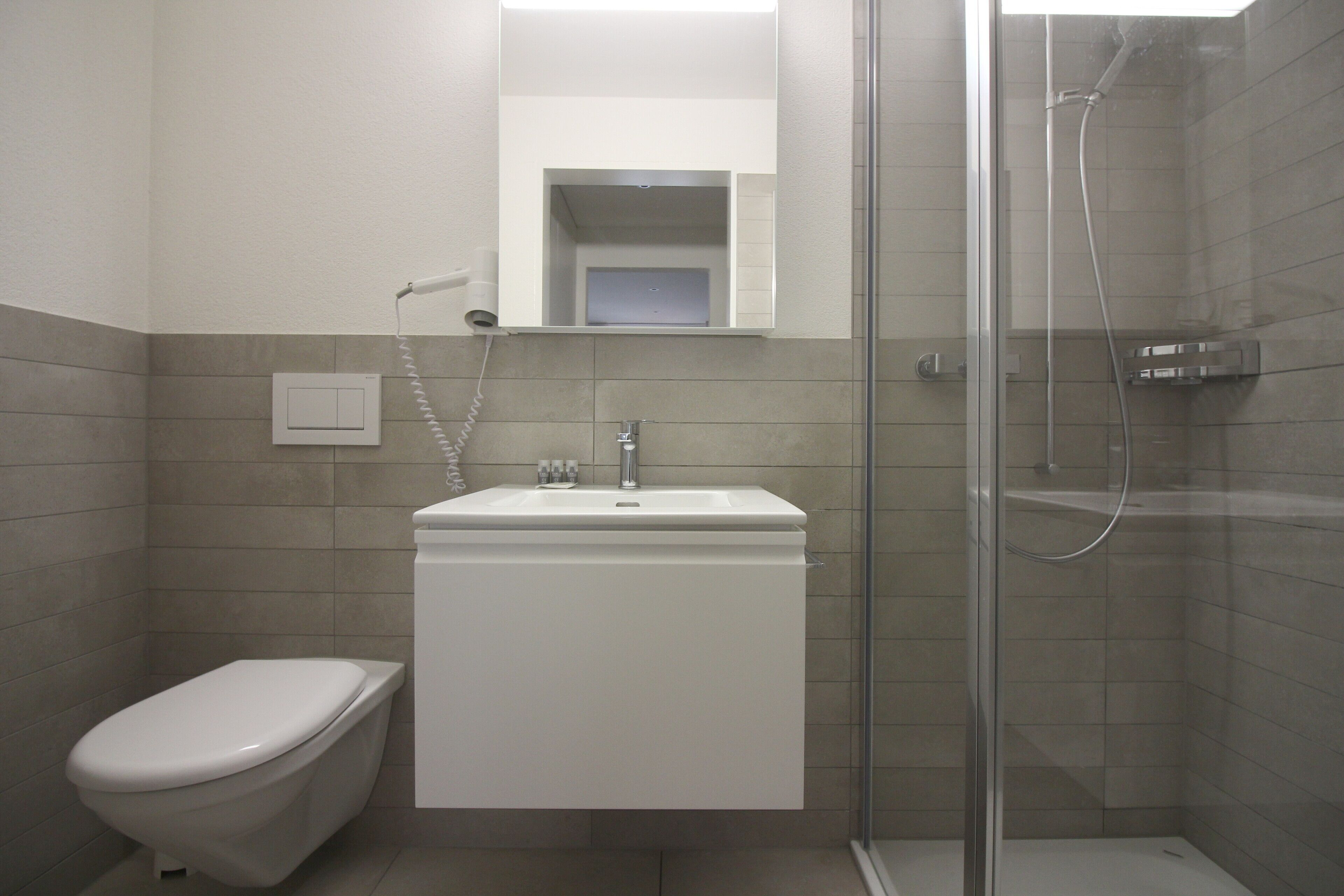A modern bathroom with a toilet, sink, and glass-enclosed shower.