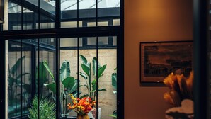 A room with large windows, a vase with flowers, and a framed picture on the wall. - Le Clos d'Emile (Bordeaux)