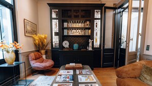 A cozy living room with a fireplace, a sofa, a coffee table with magazines, and a bookshelf with decorative items. - Le Clos d'Emile (Bordeaux)