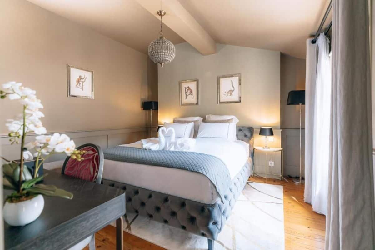 Camera da letto ordinata con un letto, comodini, un lampadario e quadri appesi al muro.