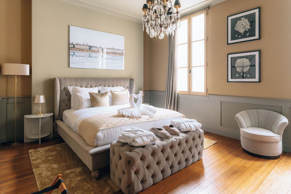 Una camera da letto con un letto grande, un lampadario, una sedia e opere d'arte alle pareti.