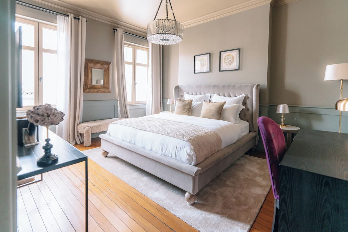 Una camera da letto con un letto grande, una scrivania, una sedia, un lampadario e una finestra con tende.