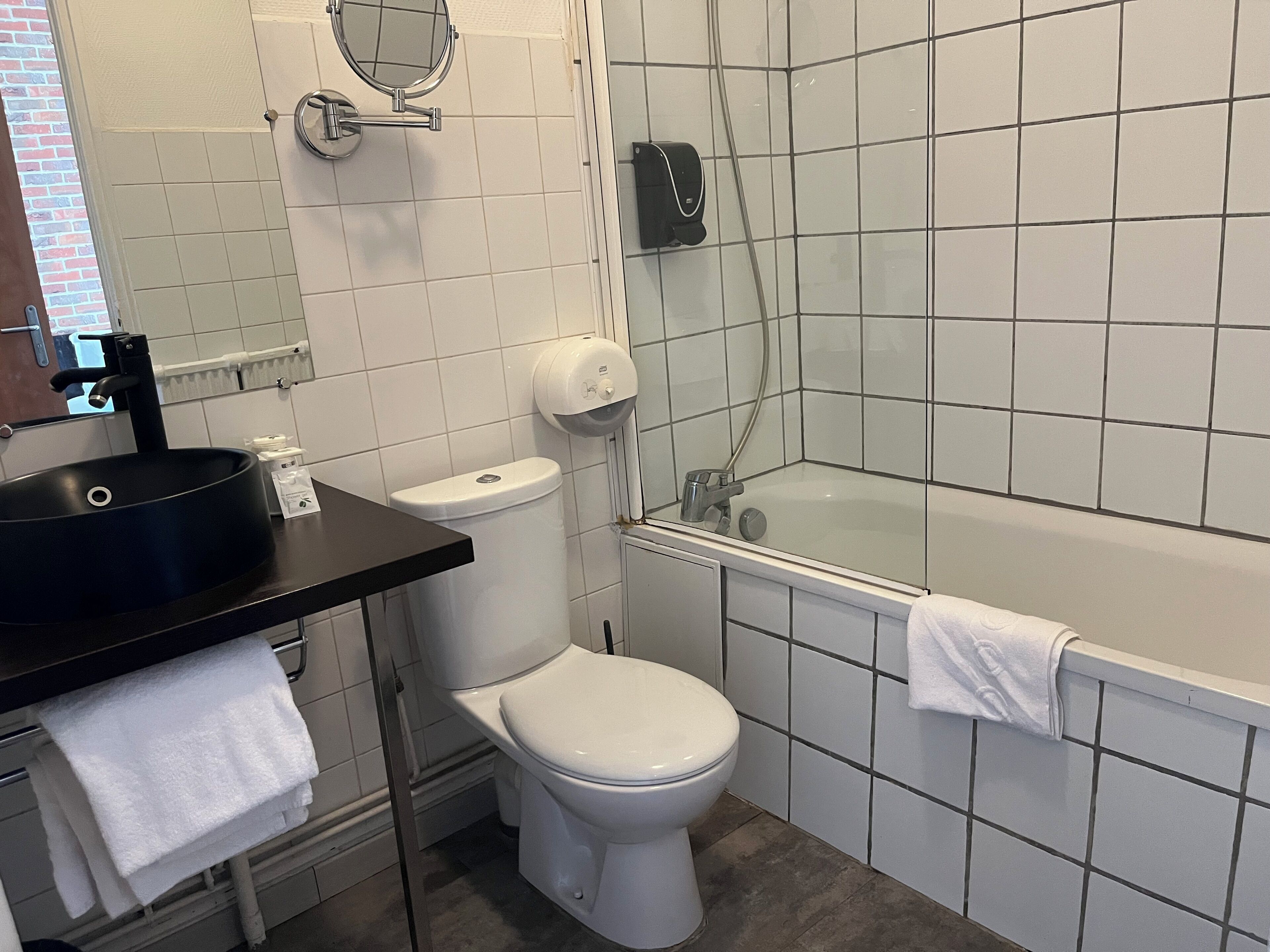 Une salle de bain avec un lavabo noir, des toilettes blanches et une baignoire.