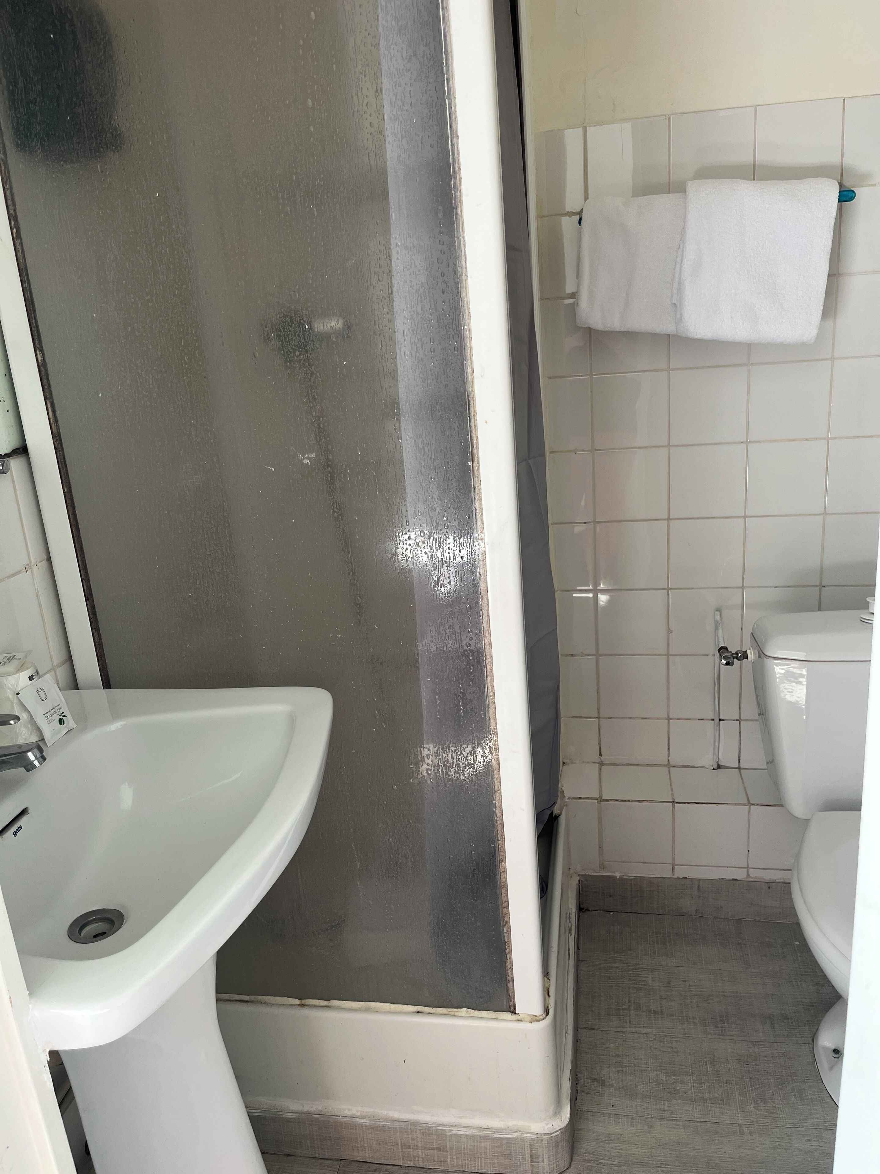 A bathroom with a white sink, a shower enclosure, and a toilet.