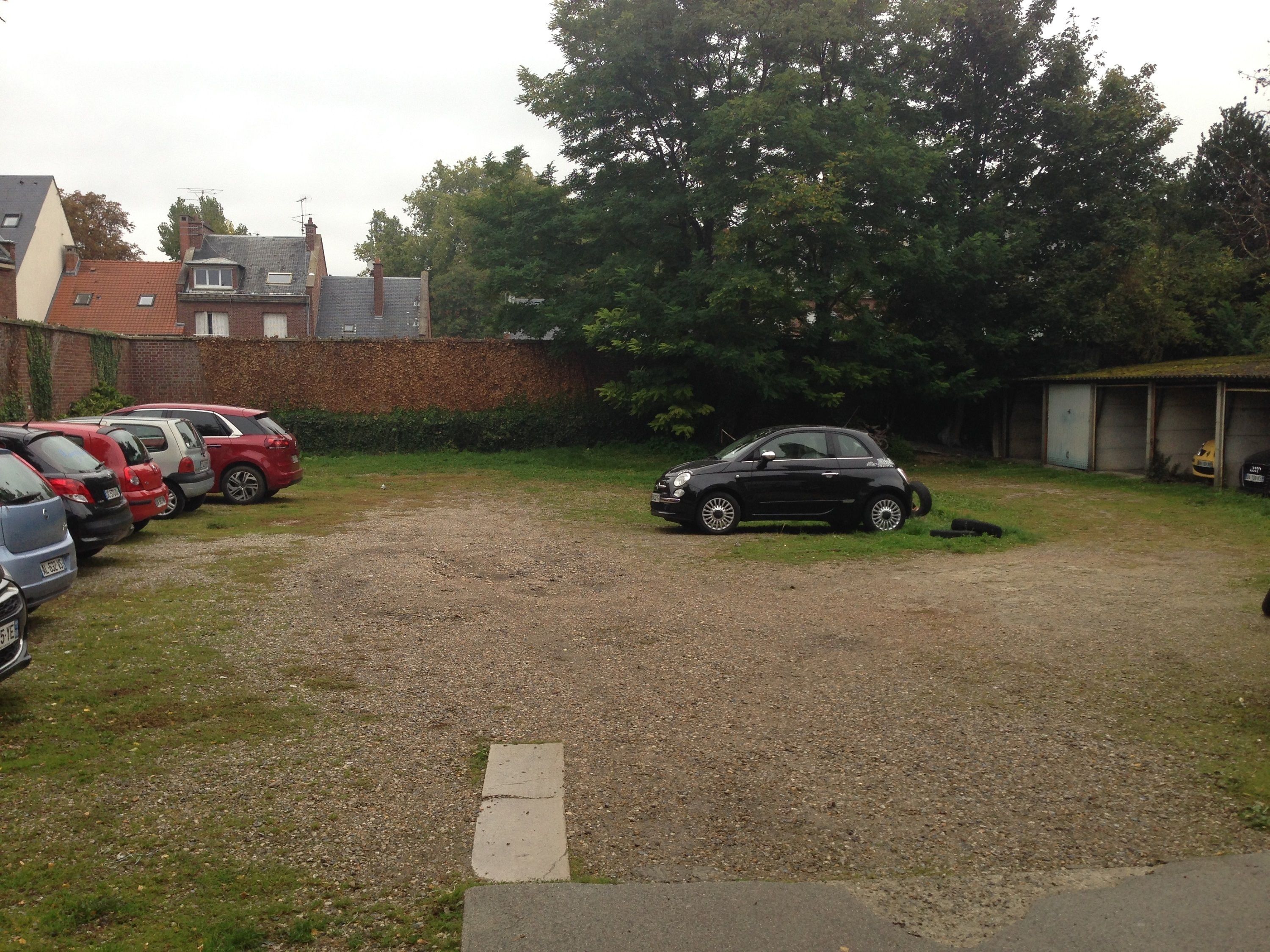 Un’area di parcheggio sterrata con diverse automobili.