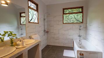 Un baño con dos lavamanos, una bañera y una ducha.