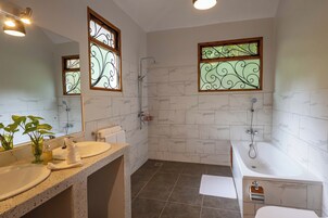 Un baño con dos lavamanos, una bañera y una ducha.