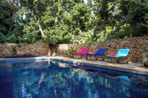 Una piscina al aire libre, sillones reclinables de piscina