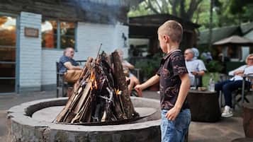 Un jeune garçon s’occupe d’un feu de bois dans un foyer en pierre.