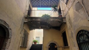 A narrow alleyway with a staircase leading to a second-floor balcony.