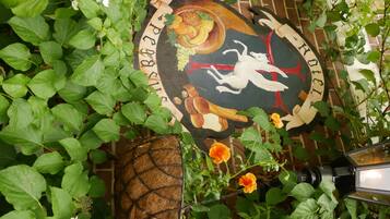 A brick wall with a mural featuring a bird, fruits, and a red banner.