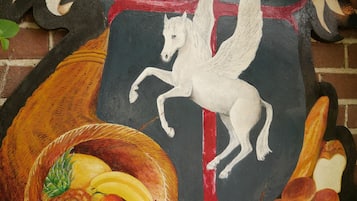 A hotel sign with a coat of arms, a white horse, and a fruit basket.