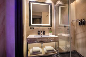 A modern bathroom with a glass-enclosed shower, a vanity with a sink, and a large mirror.